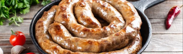 Спіраль домашньої ковбаси в сковорідці з овочами та травами