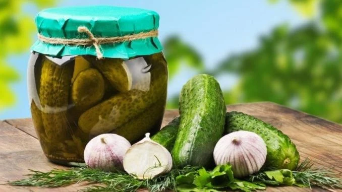 Сільні огірки в банці з цибулею та кріпом на дерев'яній дошці.