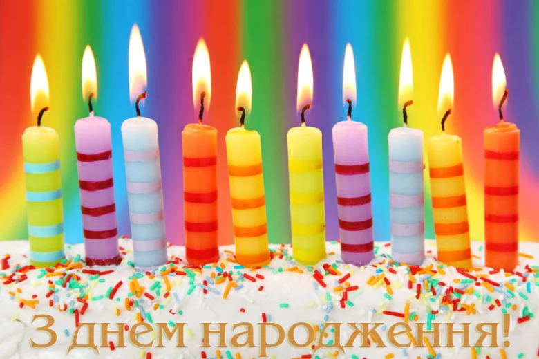 Кольорові свічки на торті з привітанням з днем народження.